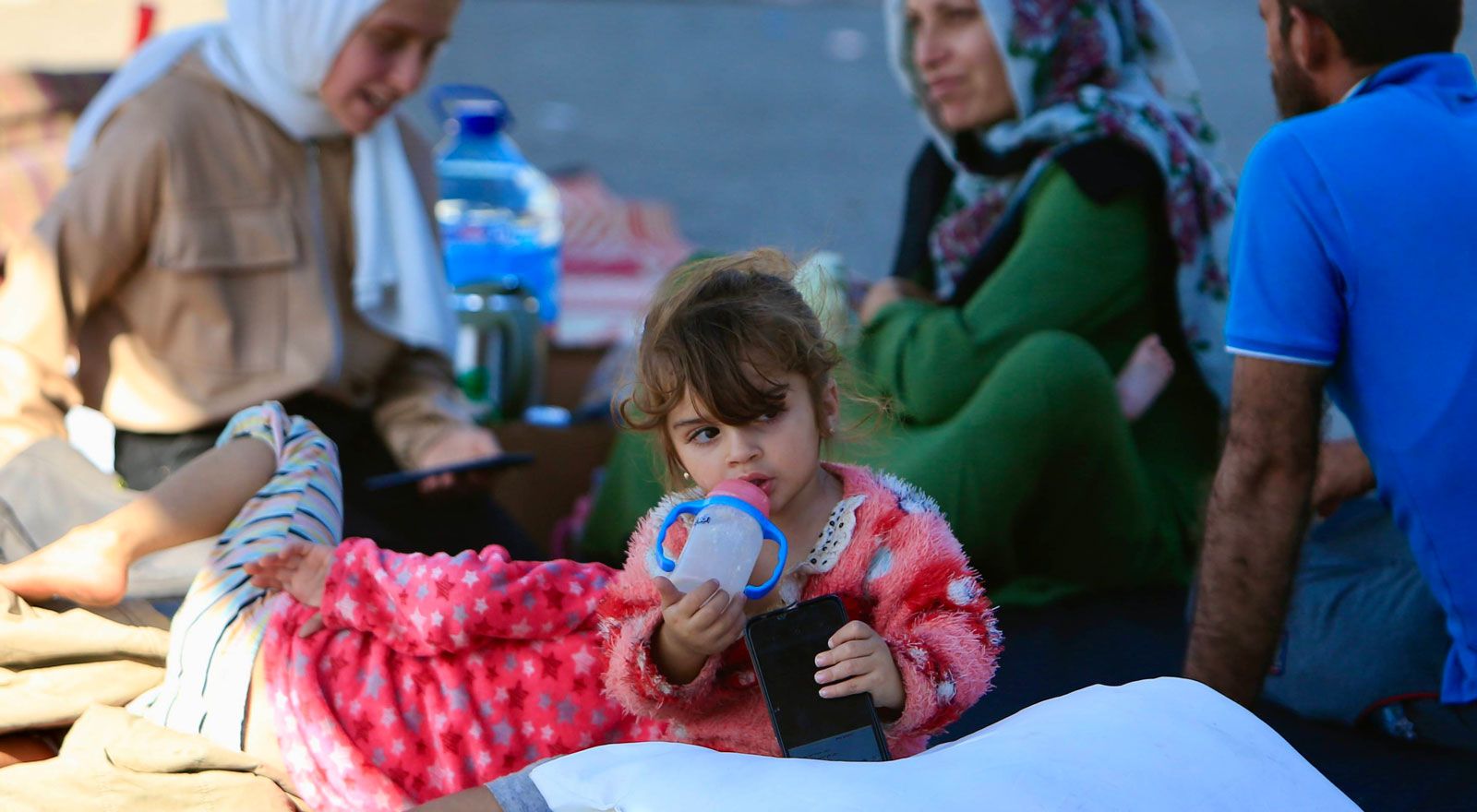 Eine geflüchtete Familie aus dem Libanon sitzt auf dem Boden, mit Mädchen im Vordergrund