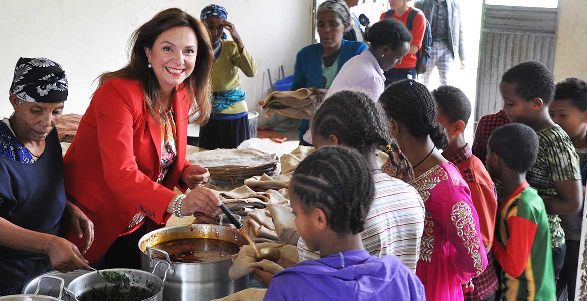 Uschi von Luttitz verteilt in einer Schule in Addis Abeba aus einem großen Topf mit einer Suppenkelle Essen an Schulkinder.