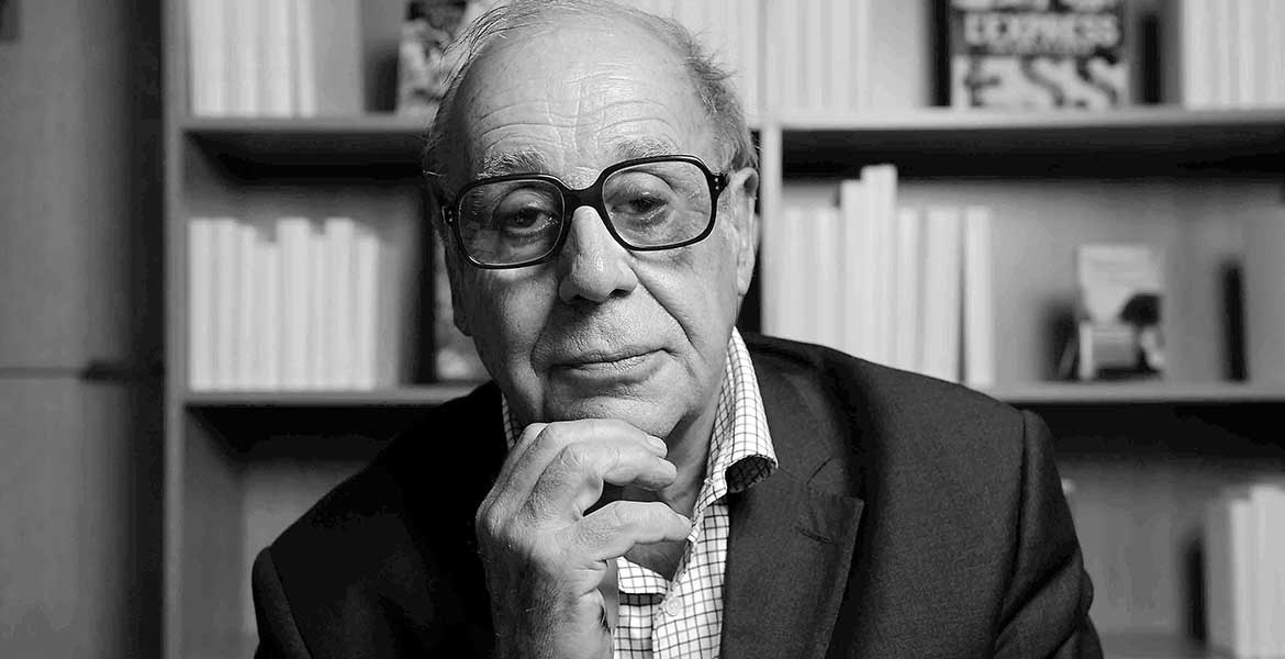 Schwarz-weiß Porträt von Jean Ziegler vor einem Bücherregal