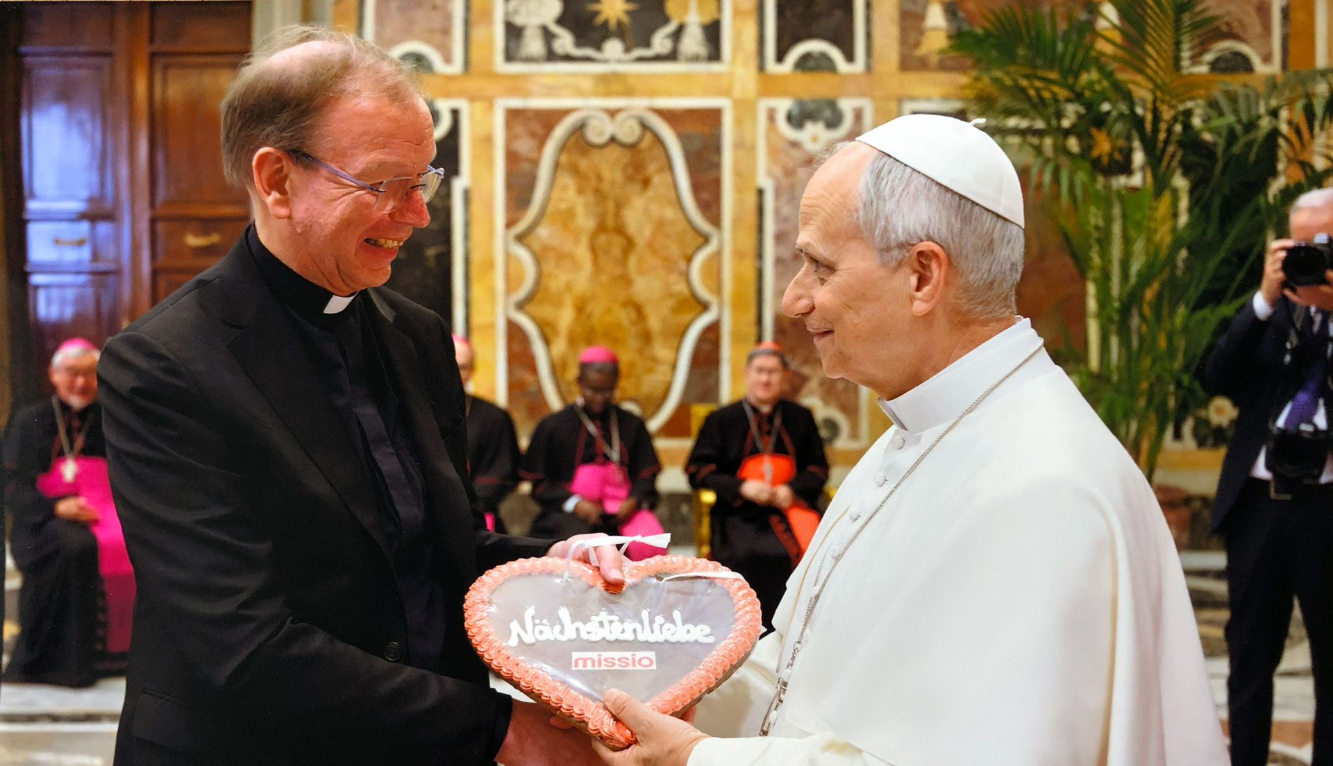 Monsignore Huber überreicht Papst Leo XIV. ein Wiesn-Herz mit der Aufschrift "Nächstenliebe"