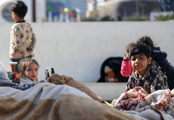 Eine geflüchtete Familie - Eltern und zwei junge Mädchen - sitzen in Beirut auf einem Sofa