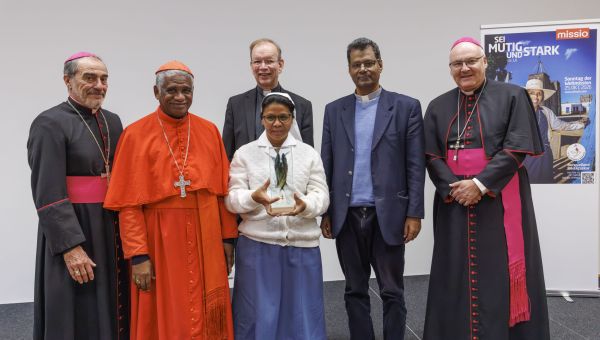 Gruppenfoto beim Empfang in Regensburg im Anschluss an den Gottesdienst zum Sonntag der Weltmission. Von links: Erzbischof Gustavo Bombin Espino, Kardinal Désiré Tsarahazana, Monsignore Wolfgang Huber (hinten), Pauline-Jaricot-Preisträgerin Schwester Rolandine Razafiarisoa (vorne), Pater Thomas Joseph, Bischof Rudolf Voderholzer. Im Hintergrund ist das Plakat des diesjährigen Monats der Weltmission mit Schwerpunkt Madagaskar zu sehen.