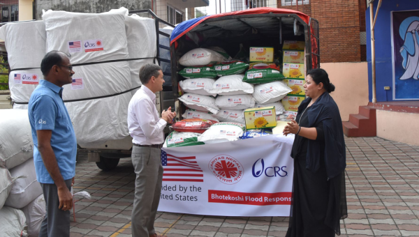 Ein kleiner Lastwagen vollbeladen mit Lebensmitteln steht auf dem Hof der Caritas Nepal in Kathmandu. Davor zwei Helfer der Caritas und Caritas-Direktorin Schwester Cecilia.
