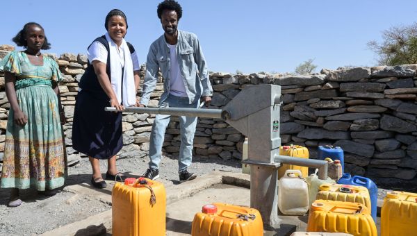 Schwester Medhin steht in Tigray an einem neuen Brunnen mit dem Projektkoordinator und einer Frau