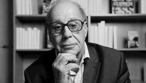 Schwarz-weiß Porträt von Jean Ziegler vor einem Bücherregal