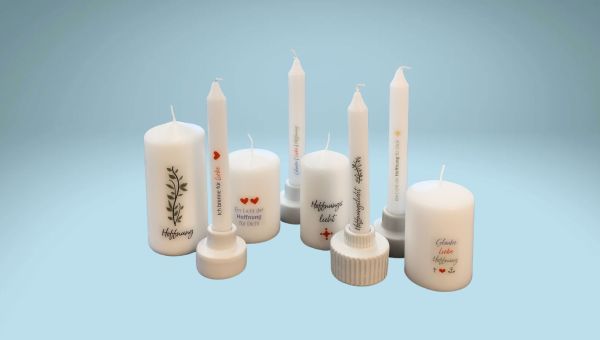 Kerzen unterschiedlicher Größe sind mit Kerzentattoos zum Thema Hoffnung verziert.