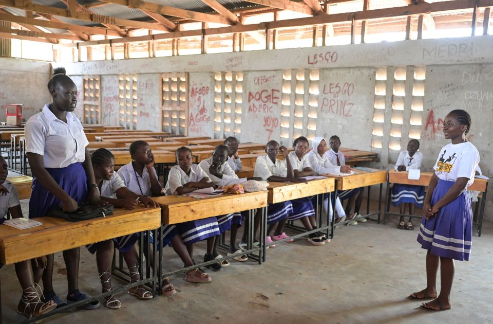 Blick in eine Schule im Flüchtlingscamp Kakuma in Kenia. Zwei junge Frauen blicken sich im einfach eingerichteten Klassenraum an