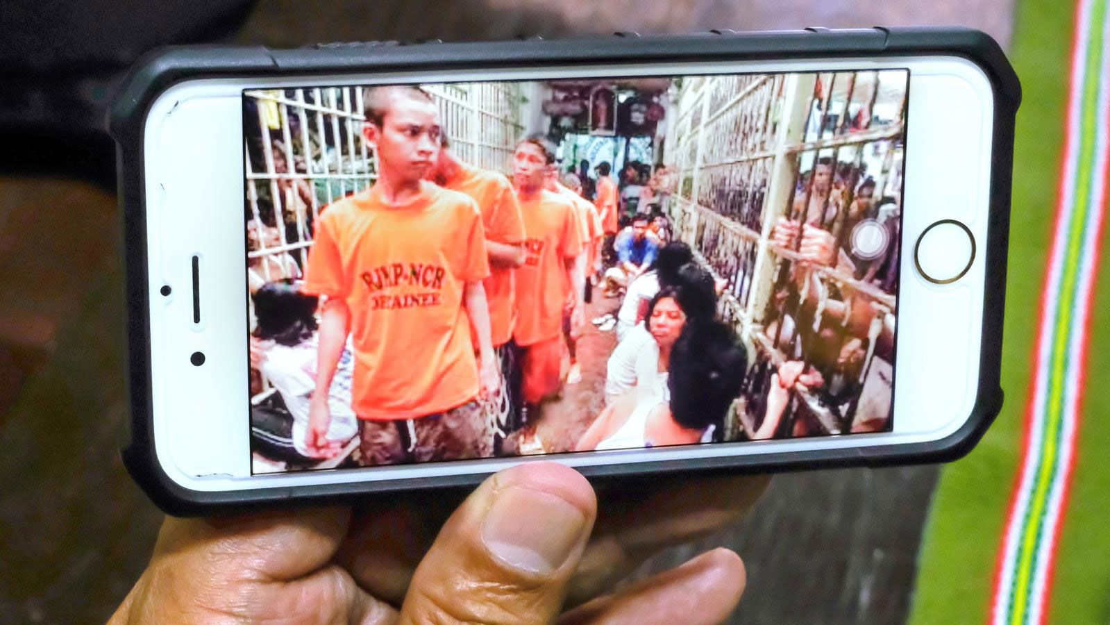 Der Generalsekretär der bischöflichen Kommission für Gefängnisseelsorge in Manila zeigt Fotos von überbelegten Gefängniszellen auf seinem Smartphone