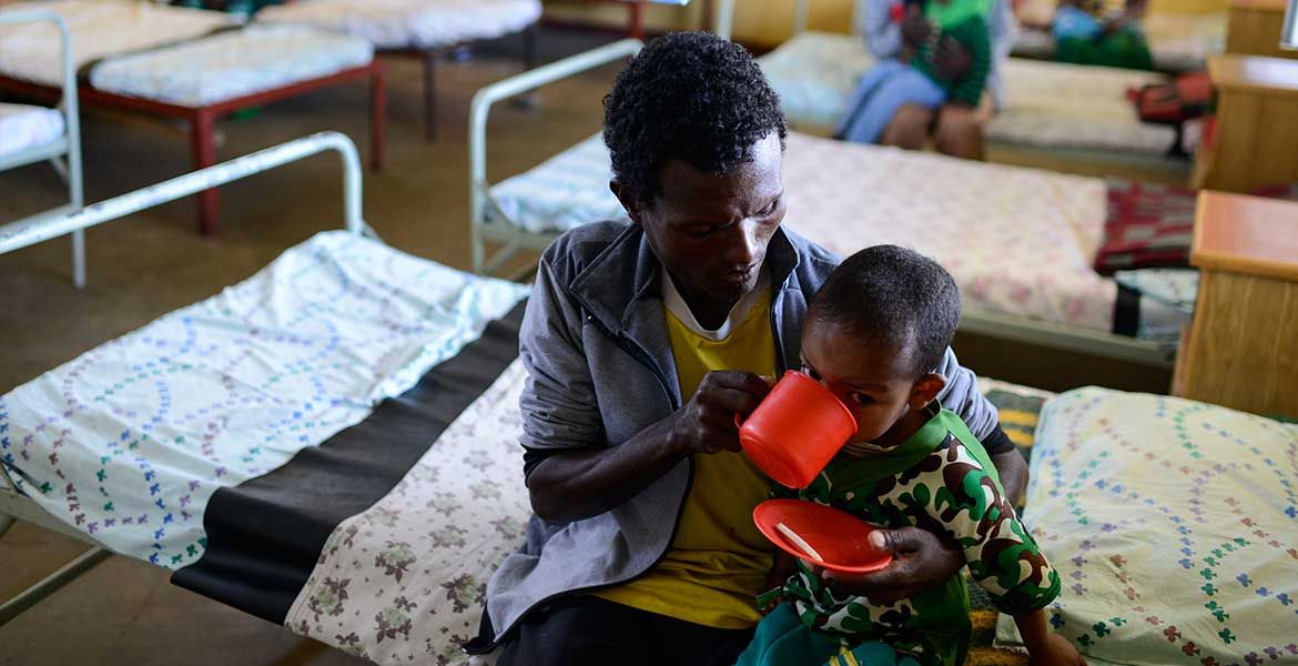 Eine augehungerte Frau gibt ihrem Kind zu trinken