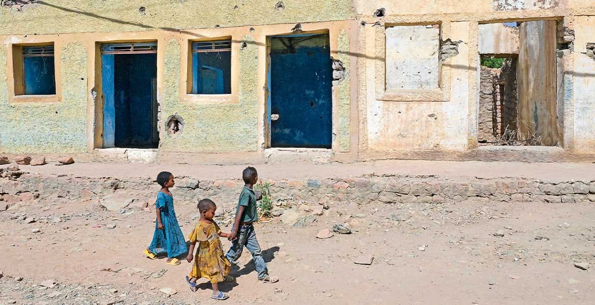 Drei Kinder laufen an einem zerbombten Haus in Tigray in Äthiopien vorbei.