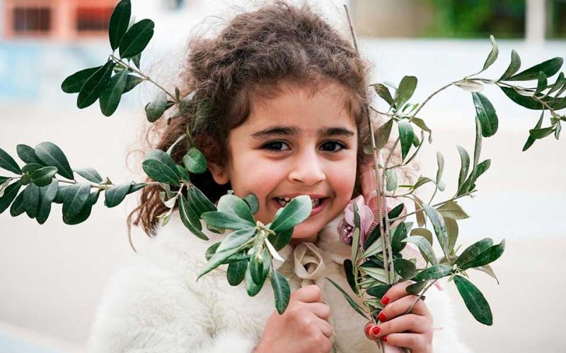 Syrisches Mädchen mit Olivenzweigen während einer Palmsonntagsprozession des Don-Bosco-Zentrums in Damaskus, Syrien.