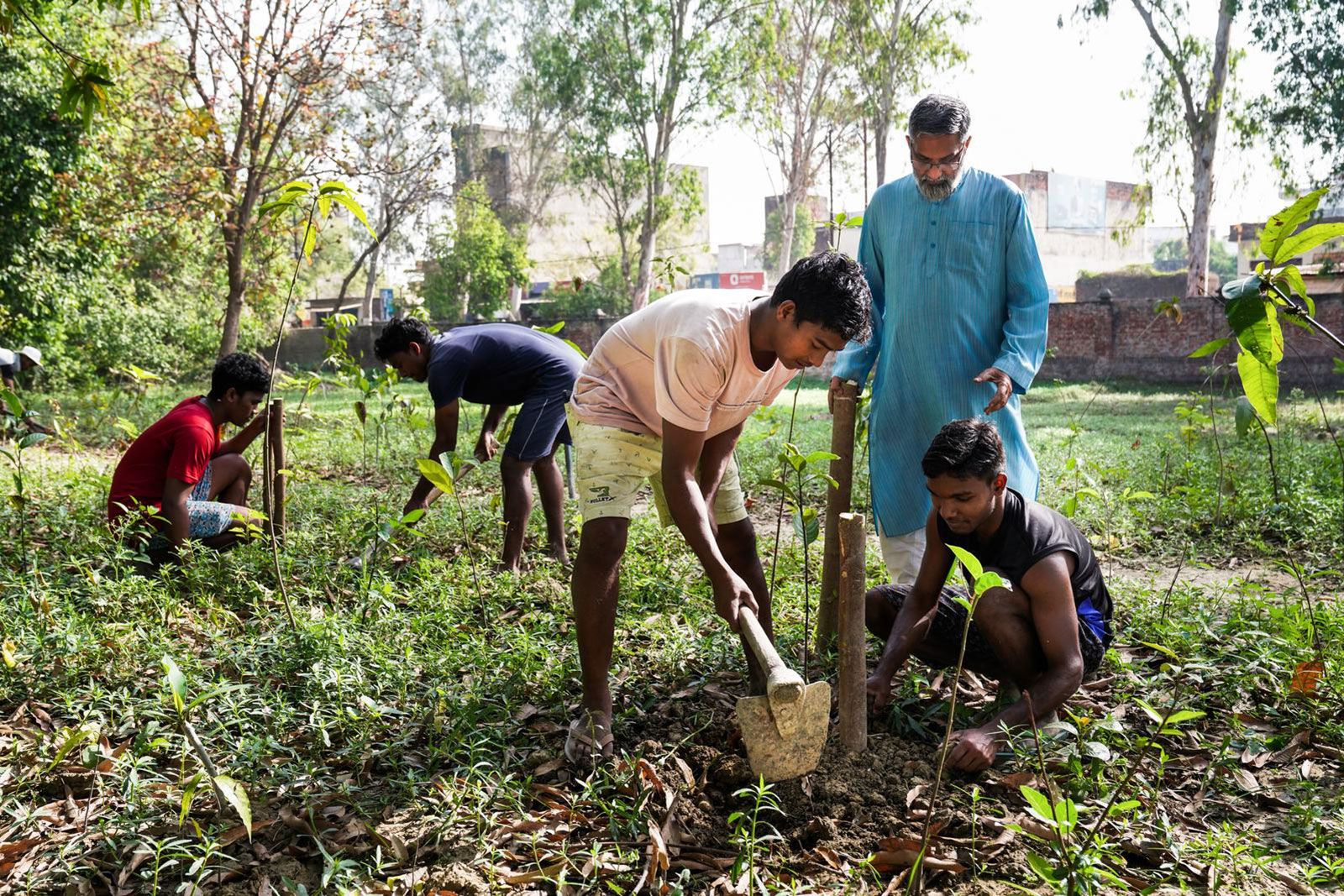 Father Anand Matthew pflanzt mit jungen Menschen im indischen Varanasi Bäume