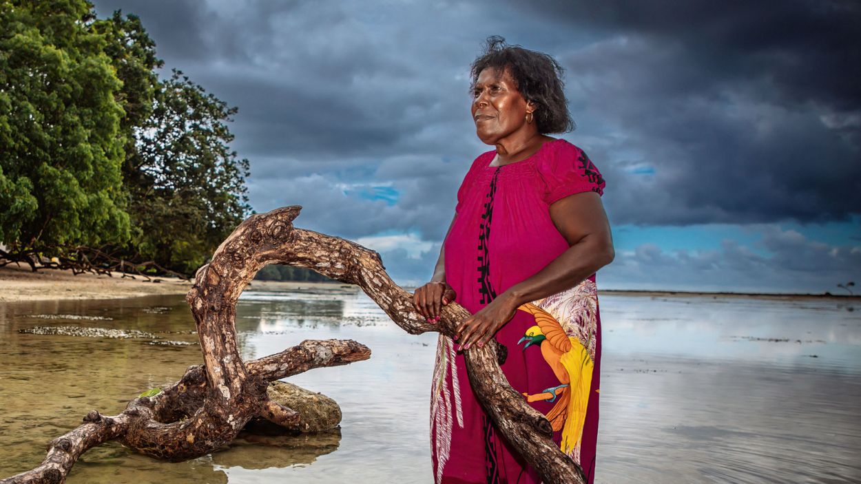 Eine Frau aus Papua-Neuguinea steht vor dramatischem Wolkenhimmel im Wasser