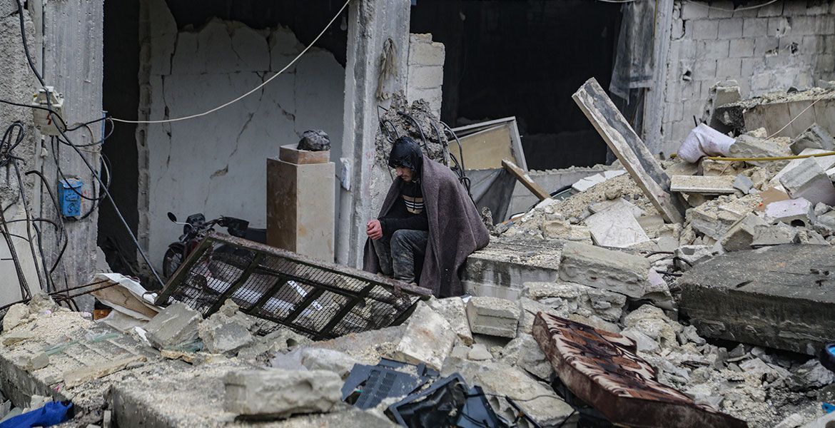 Mann sitzt inmitten eines eingestürzten Hauses in Aleppo