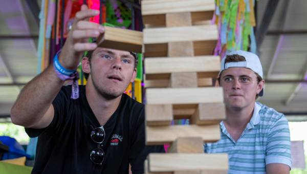 Zwei junge Männer bauen einen Holzturm aus Jenga-Steinen.