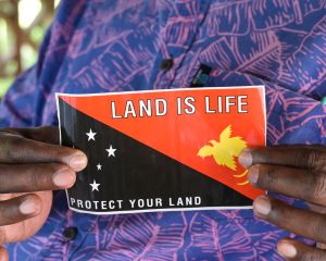 Eine indigene Frau hält die Flagge von Papua-Neuguinea hoch