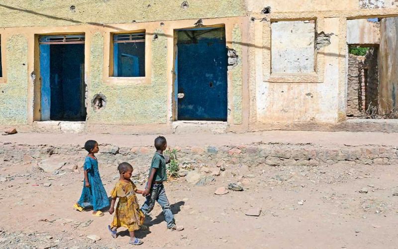 Drei Kinder laufen an einem zerbombten Haus in Tigray in Äthiopien vorbei.